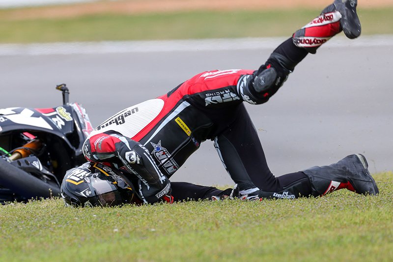 Motorcycle racer hitting helmet on grass